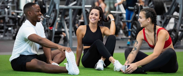 Friends stretching and smiling on turf in VASA Fitness gym