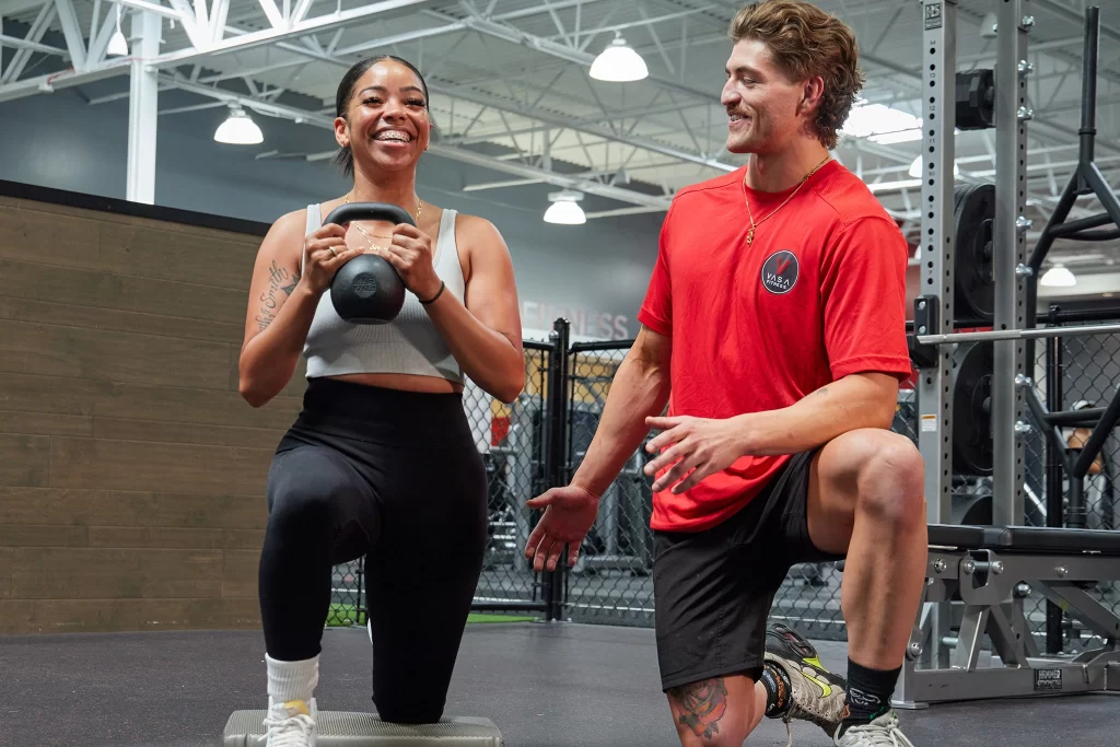 A female athlete doing a kettlebell exercise with a personal trainer at VASA Fitness