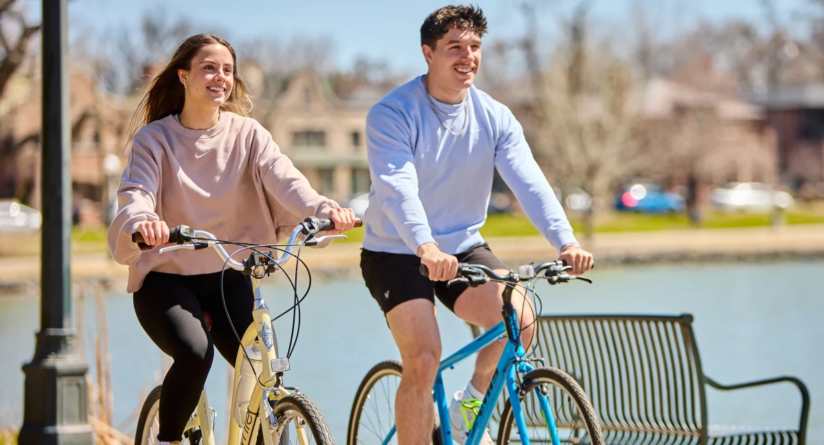 Two young adults riding bicycles in the park