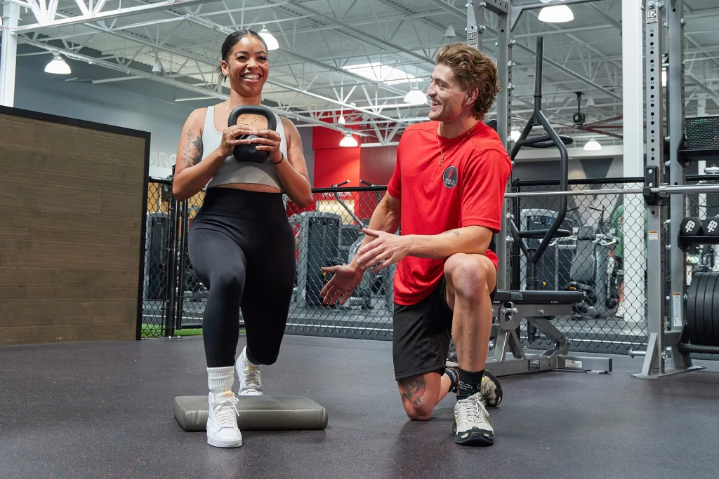 Female athlete doing a kettlebell exercise with a personal trainer at VASA Fitness